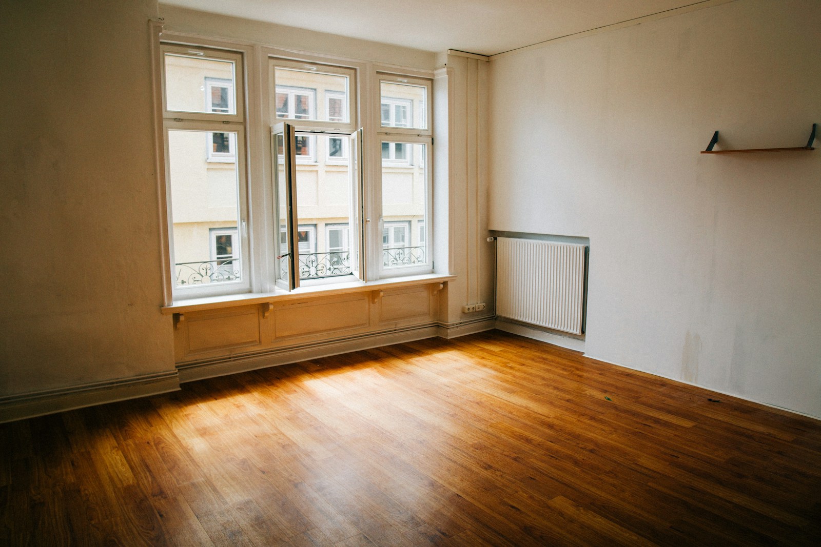 Empty room with wooden floor and large window, vacant property